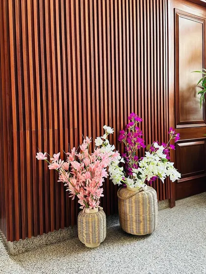A detail shot focusing on the texture of the wood-fluted wall and the colorful artificial flowers that add a pop of color to the entrance.