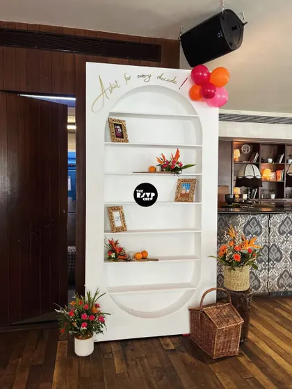 A modern and elegant shelving unit used as a display, decorated with fresh flowers, oranges, and framed photos.