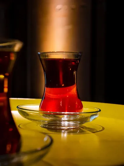 A beautiful shot of Turkish tea, with the light hitting the glass to create a jewel-like red glow. The focus is on the rich color and clarity of the tea.
