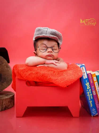 A tiny scholar dreaming of big ideas. The little glasses and stack of books add a playful and intellectual touch to this newborn portrait.
