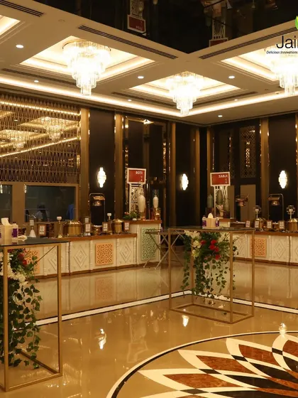 A panoramic view of a grand banquet hall setup. The combination of high ceilings, crystal chandeliers, and our elegant food stations creates a truly luxurious dining environment.