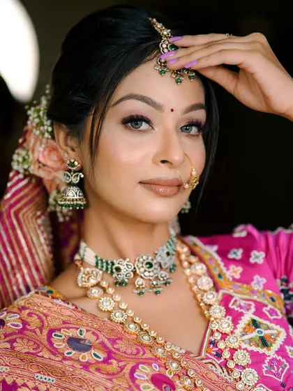 A close up of a traditional Gujarati bridal look. The focus is on the intricate jewelry and the classic makeup with a neat floral bun.