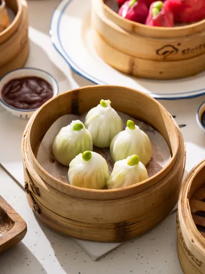 A close-up of delicate edamame and truffle dumplings. The focus is on the unique shape and the single edamame bean on top.