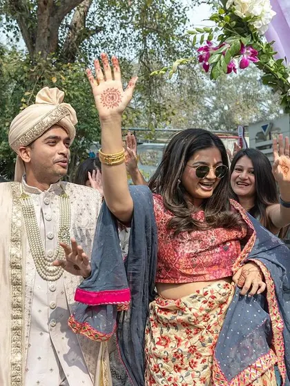 The groom and his sister leading the baraat with waves and smiles.