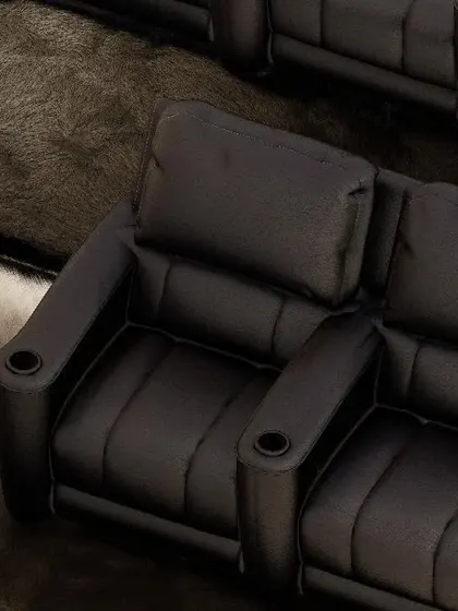An overhead close-up of our dual-seater recliner in black, showing the plush headrest and armrests with built-in cup holders. This is ergonomic design meeting cinematic convenience.
