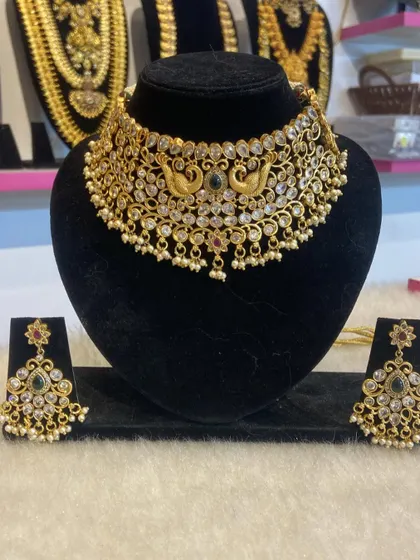 A peacock-motif choker with white stones and pearl drops. This elegant piece is a versatile rental option for various occasions.
