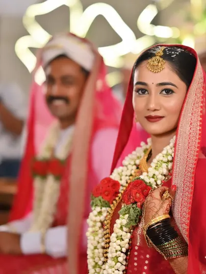 A beautiful portrait of the bride during her muhurtham, with the groom in the background. Her makeup is classic and bold.
