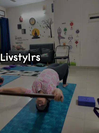 A client performs a supported bridge pose using a yoga wheel and stick. This creative use of props helps to deepen the backbend and open the shoulders simultaneously.