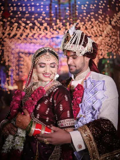 A joyful candid moment between the bride and groom, with the groom's currency garland adding a traditional touch to this happy wedding portrait.