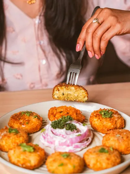 A lifestyle shot showing a dahi kebab being cut into. This interactive style of food photography helps customers imagine the texture and taste, making the dish more relatable and tempting.