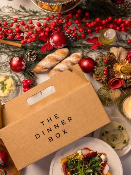 Our signature packaging is designed to protect the integrity of your meal and build anticipation for the feast within. Here, our box is pictured as part of a festive tablescape, ready to be the star of the celebration.