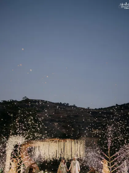 A breathtaking wide shot of the couple under a sky of falling petals, with the Lonavala hills in the background, creating a truly epic wedding portrait.