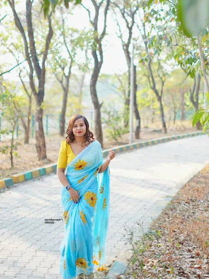 A cheerful light blue saree with a sunflower print, paired with a bright yellow blouse. A perfect look for a sunny day.
