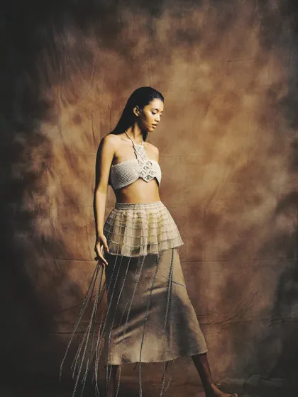 A full-length shot showcasing a conceptual look with a wet-hair effect and bronzed, glowing skin for a raw, elemental vibe.