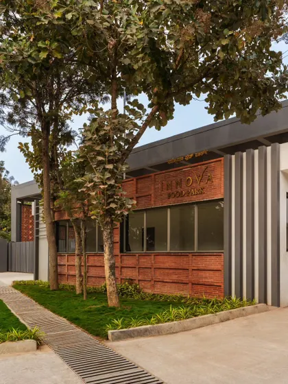 A view of the Campus Biovet entrance, where brass branding adds a touch of sophistication to the exposed brick facade. The surrounding landscaping and a mini rock garden soften the industrial character and create a welcoming feeling.
