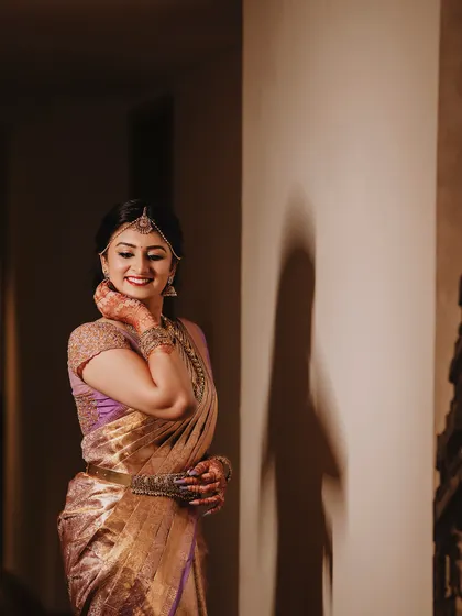 Bride Ishwarya in a quiet moment before her ceremony. The soft lighting highlights the beautiful fall of her reception saree.