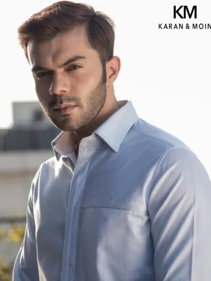 A close-up of a crisp, light blue formal shirt. Woven for warm days and cooler moments, this piece is summer's quiet masterpiece, offering a calm kind of confidence.