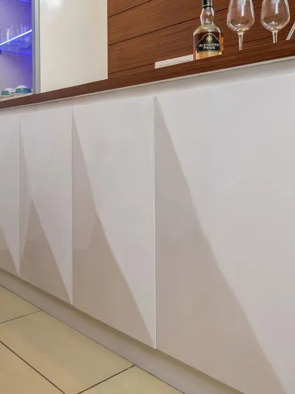 A detail shot of the 3D geometric pattern on the glossy white cabinet doors of the crockery unit. This adds a subtle layer of texture and sophistication.