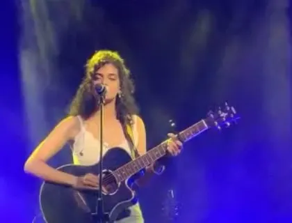 A clear shot of me playing my black acoustic guitar under the blue stage lights. This is my go-to setup for big stage solo performances.
