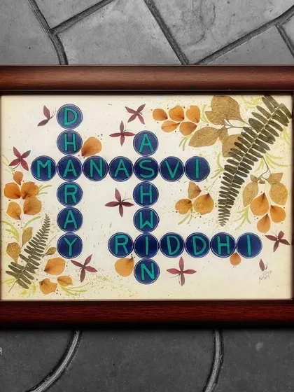 A creative crossword-style nameplate for a family, combining their names in a Scrabble-like grid. I used pressed and dried flowers and leaves to give it a rustic, natural feel.