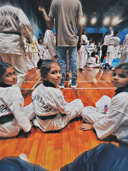 A candid moment between matches, where young Taekwondo practitioners rest and bond, showcasing the friendships built through martial arts.