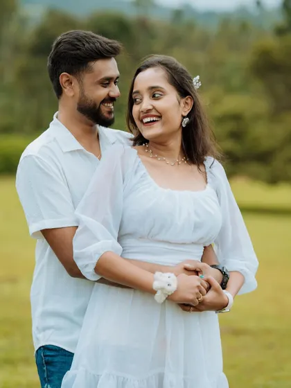 A happy, candid portrait of a couple in a lush green field. Their natural smiles and comfortable embrace are what we strive to capture in every pre-wedding shoot.
