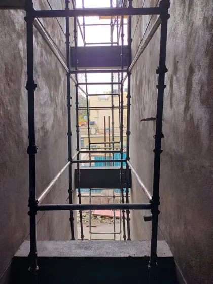 A view from within a building's core during construction, looking up through multiple levels of scaffolding. This perspective highlights the vertical scale of the project and the temporary structures needed for construction.