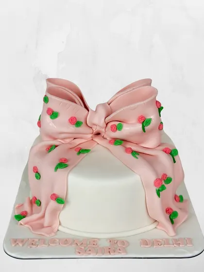 A cake that's wrapped like a present. This design features a large, cascading pink fondant bow decorated with tiny, hand-piped roses.