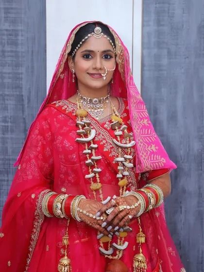 The bride is ready for her Pheras, adorned with a traditional coconut garland. The makeup is designed to be resilient and beautiful through all the ceremonies.