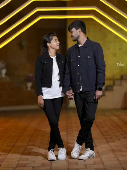 A stylish night shot of a couple holding hands under bright yellow lights. The industrial-style lighting creates a modern and edgy look.