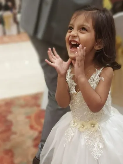 That look of pure excitement says it all. This exquisite white gown with delicate floral appliqué on the bodice and a full tulle skirt is the kind of dress that makes a little girl feel like she's in a fairytale.