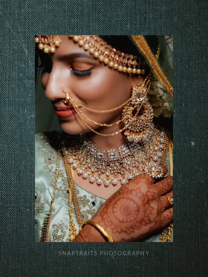 A close-up shot focusing on the bride's exquisite jewelry, from her nose ring to her layered necklaces.