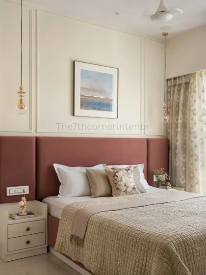 In this cozy bedroom, neutral tones create a tranquil foundation. The design is elevated by a rich, dusty rose upholstered headboard and curated art, evoking a sense of calm and beauty.