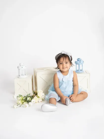 A happy smile from a little girl in a pretty blue dress. Our all-white studio setup is perfect for creating bright, airy, and timeless portraits.