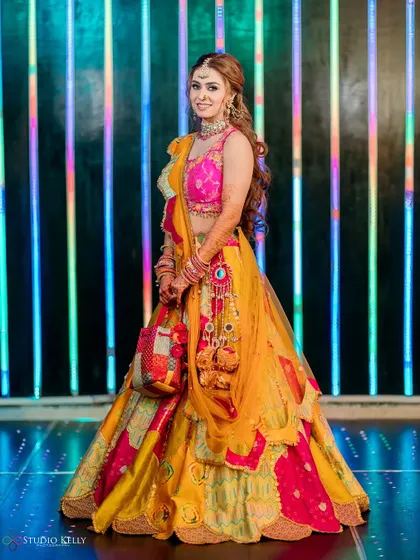 A full-length shot of the bride in her colorful Mehendi outfit, looking vibrant and happy.