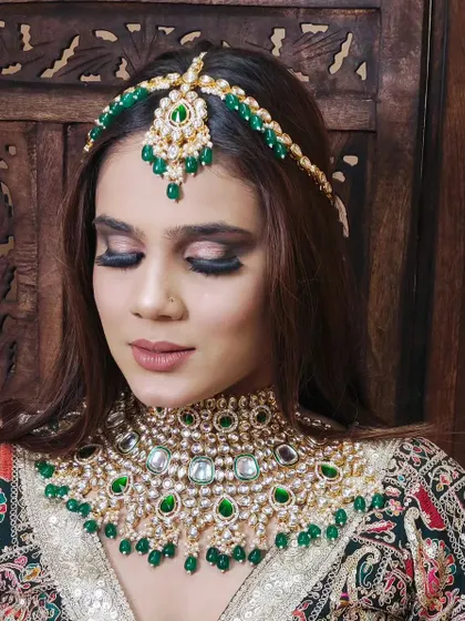 A close-up of a stunning green beaded Kundan choker and matha patti. The intricate design and vibrant colour make this a standout piece.