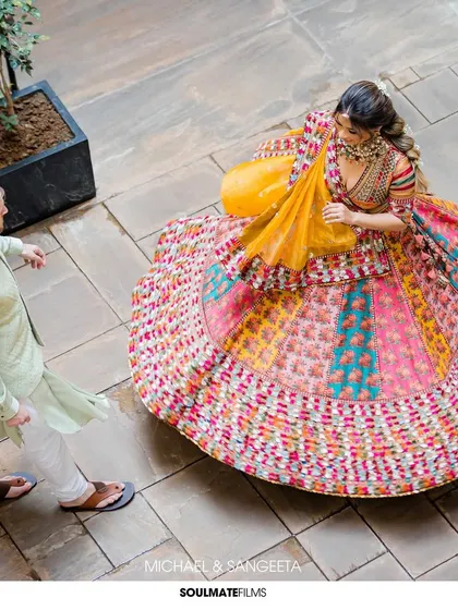 A dynamic overhead shot of the bride twirling in her multi-colored Mehendi lehenga. It captures the movement and vibrancy of her outfit and her joyful spirit.
