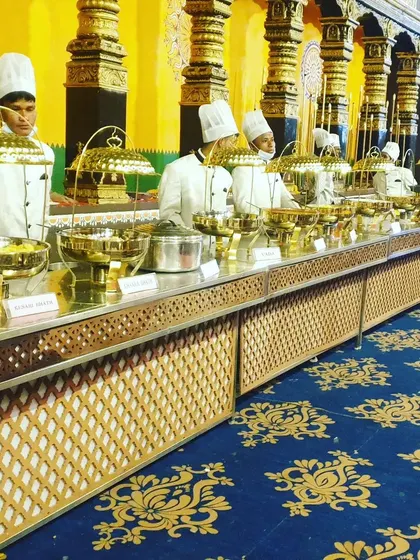 A frontal view of a long buffet counter with my staff in uniform, ready for service. The consistent presentation and traditional serving ware reflect my high standards for event catering.