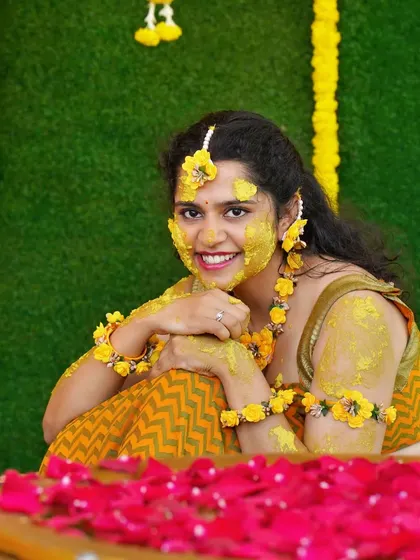 A joyful candid of the bride during her Haldi, with a bright smile and turmeric on her face.