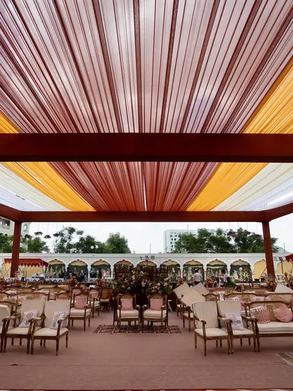 A wide view of the Bhaat ceremony setup, with a colorful draped ceiling and elegant seating arrangements.