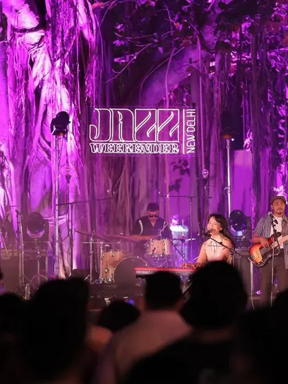 A live band captivates the audience on the Jazz Weekender stage. The purple lighting against the natural backdrop of the banyan tree is a signature part of the festival's visual and atmospheric design.