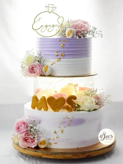 Engagement season is here, and this lilac and white cake is one of my favorites. It features a light-up acrylic tier, fresh flowers, and edible gold leaf, creating a romantic and eye-catching design.