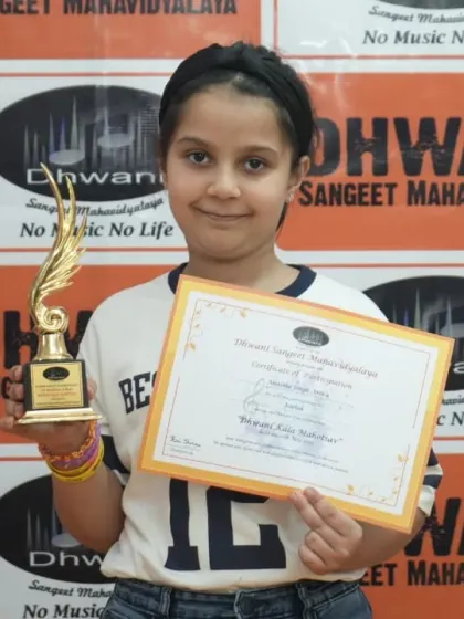 A young girl proudly holds her certificate and trophy.
