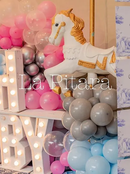 Large marquee letters spelling 'OH BABY', surrounded by pink, blue, and silver balloons and a carousel horse prop.