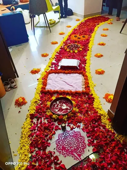 The flower petal walkway for a baby's welcome home ceremony, with traditional elements like a 'kalash' and 'rangoli'.
