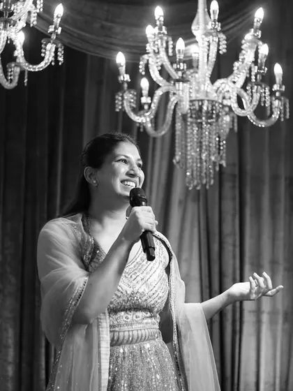 A timeless black and white portrait. It showcases a moment of genuine connection with the audience, framed by elegant chandeliers.