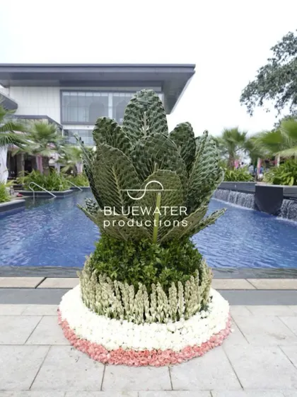 A unique floral sculpture made of woven coconut fronds and flowers, placed by the poolside.