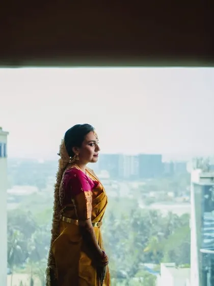 A serene bridal portrait by the window. The bride, in her traditional South Indian saree, looks out at the Mumbai city-scape from her room at the Novotel, a moment of quiet contemplation before the ceremony.