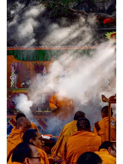 Incense smoke billows through the air during a Buddhist ritual, partially obscuring the monks. This atmospheric shot conveys the sensory details and sacred traditions of the ceremony.