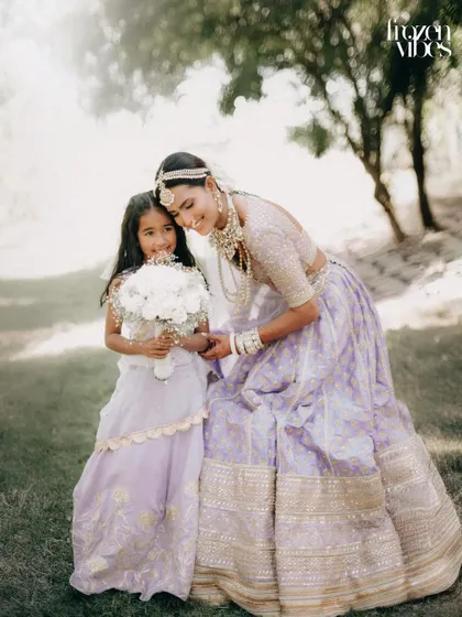 A bride sharing a moment with her flower girl in a misty, beautiful outdoor setting. The location adds a magical, ethereal quality to the photo.